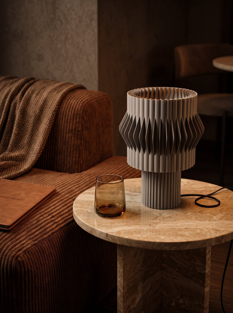 Lámpara de mesa Kyro Gris encendida sobre una mesa auxiliar junto a un sofá